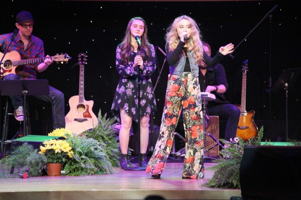 Sabrina Carpenter performing live on stage with musicians during a concert featured in Sabrina Carpenter albums