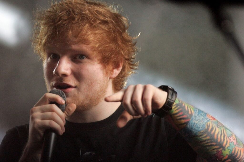 Ed Sheeran with his guitar, representing his albums and the stories behind his music